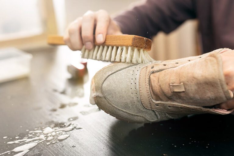 Ein heller Sneaker wird mit einer Bürste gereinigt.