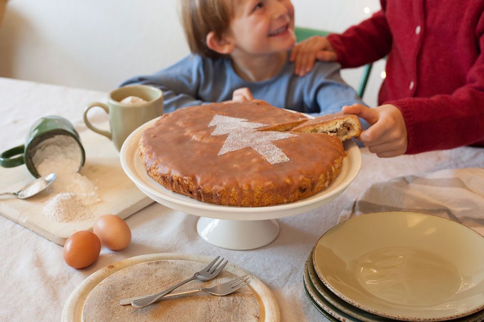 Zwei Kinder naschen von dem Tassenkuchen, der vor ihnen auf dem Tisch steht.