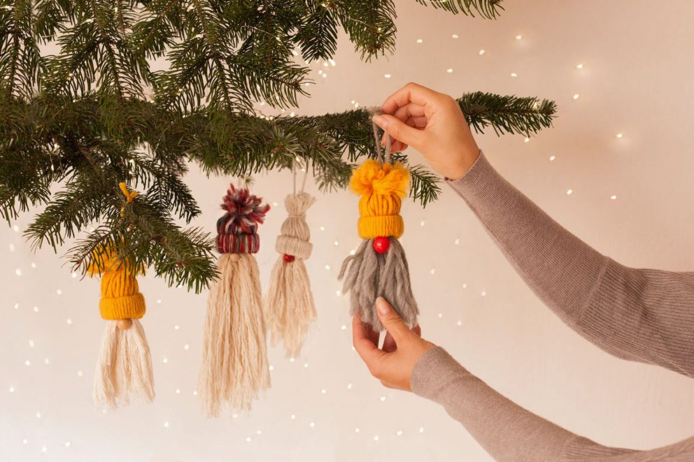 Die kleinen Weihnachtswichtel werden von einer Frau als Baumschmuck aufgehängt.