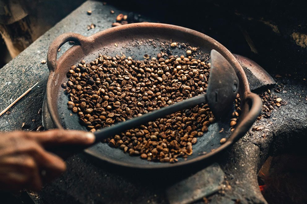Kaffeebohnen werden in einer Pfanne geröstet.