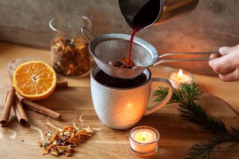 Das selbst gemachte Glühweingewürz wird durch ein Sieb vom Glühwein getrennt.