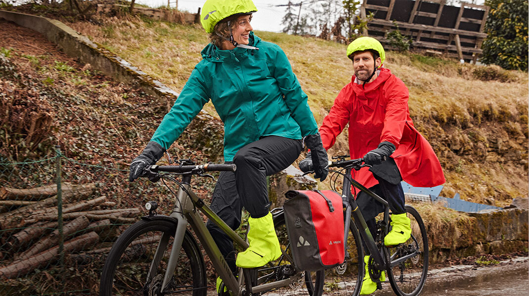 Frau und Mann tragen wetterfeste Fahrradbekleidung und machen eine Fahrradtour.