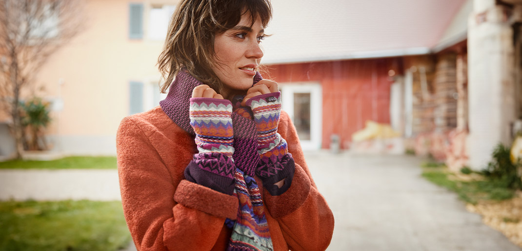 Frau eingekuschelt im Winter mit Strickschal und Strickstulpen