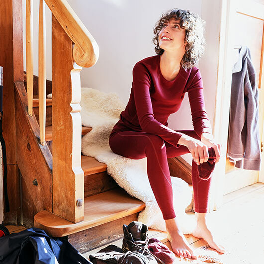 Frau in Bio-Funktionsunterwäsche zieht sich für eine Wanderung an.