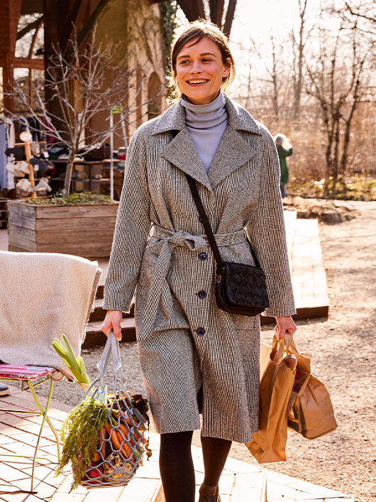 Frau in einem Mantel aus Bio-Wolle mit Einkäufen.