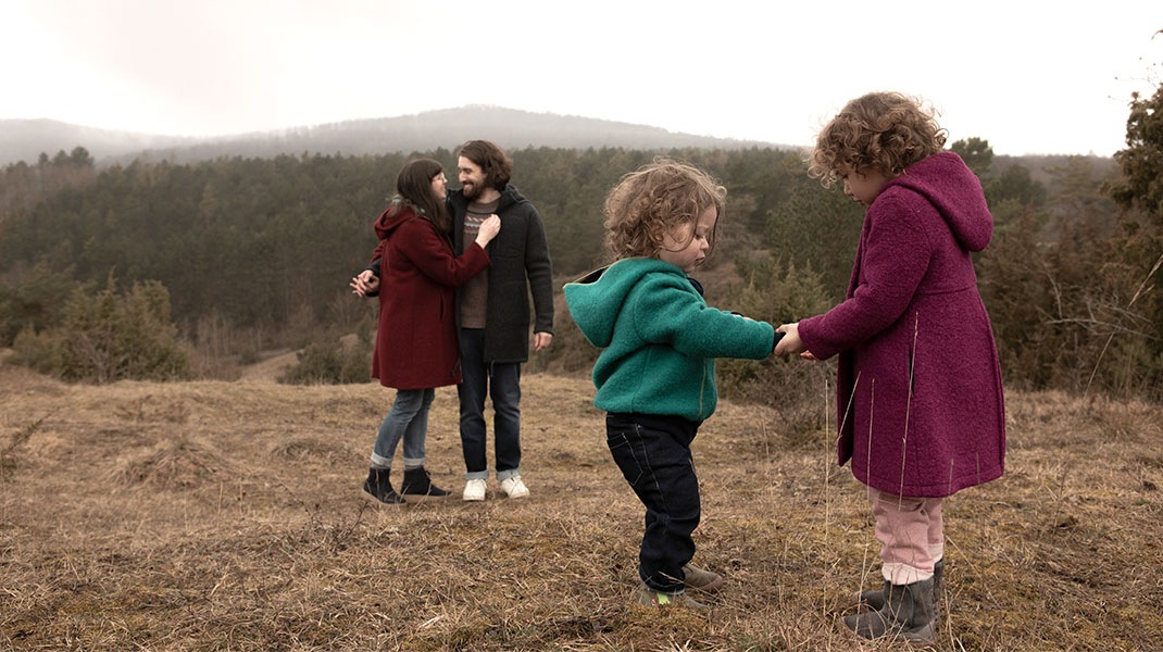 Eine Familie mit zwei Kindern mit Jacken und Mänteln aus Wollwalk in einer herbstlichen Landschaft.