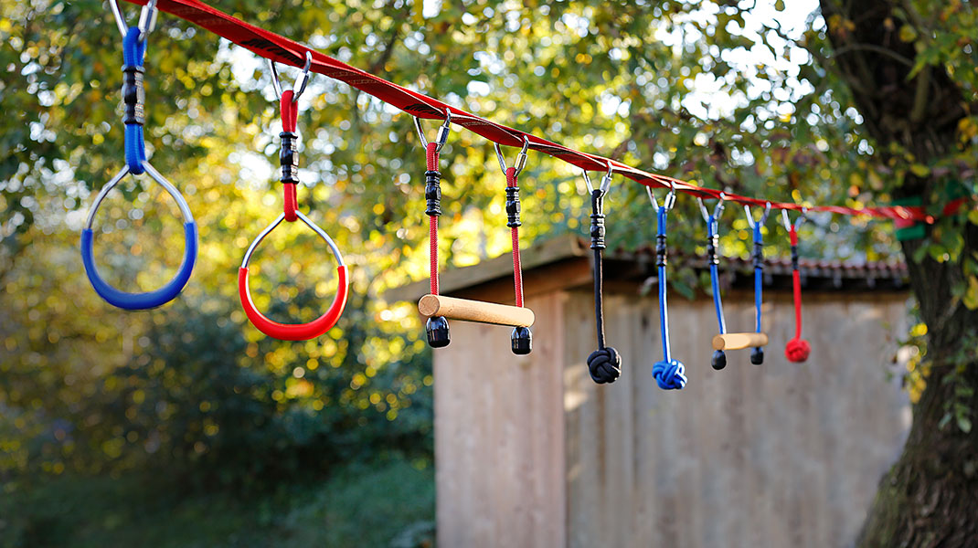 Slackline für Kinder mit verschiedenen Griffmöglichkeiten im Garten aufgespannt