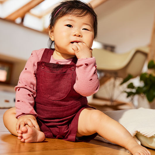 Baby in Langarmshirt und kurzer Latzhose von Waschbär