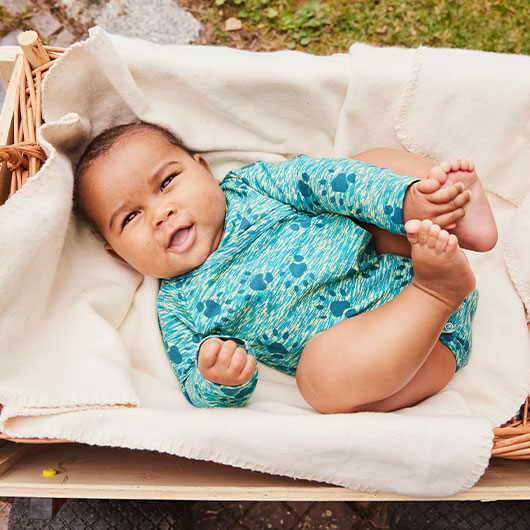 Baby in pfirsich-farbenem Ajour Body aus Bio-Baumwolle