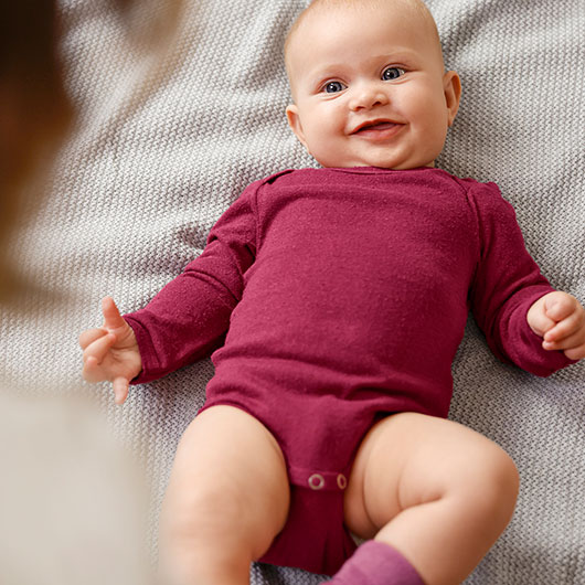 Baby in pfirsich-farbenem Ajour Body aus Bio-Baumwolle