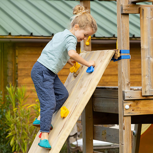 Mädchen klettert draußen an Kinder-Klettergriffen