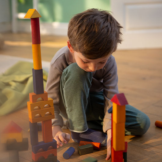 Junge spielt mit Natur-Bauklötzen aus Holz