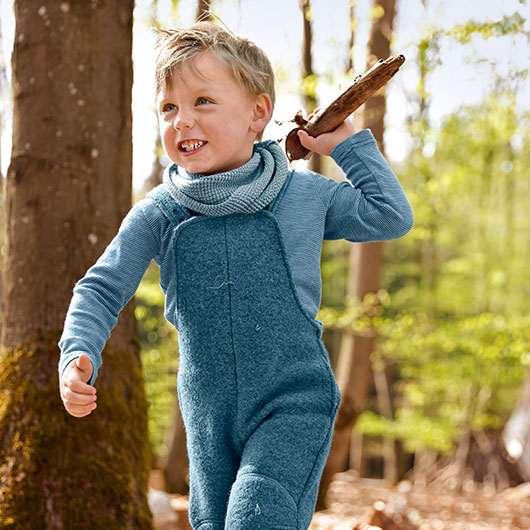 Junge im Wald in blauer Bio-Wollwalk-Latzhose
