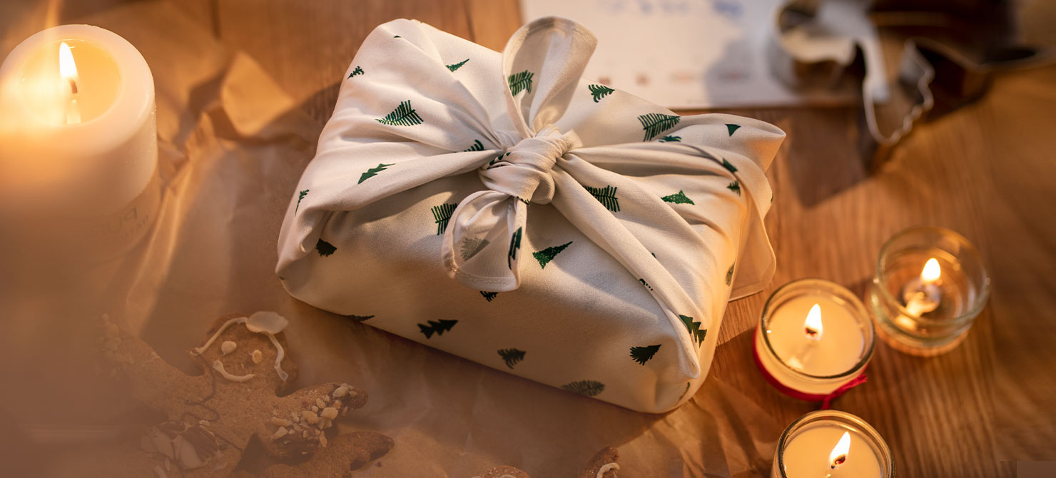 Eingepacktes Geschenk, auf einem weihnachtlichen Tisch mit Kerzen drapiert